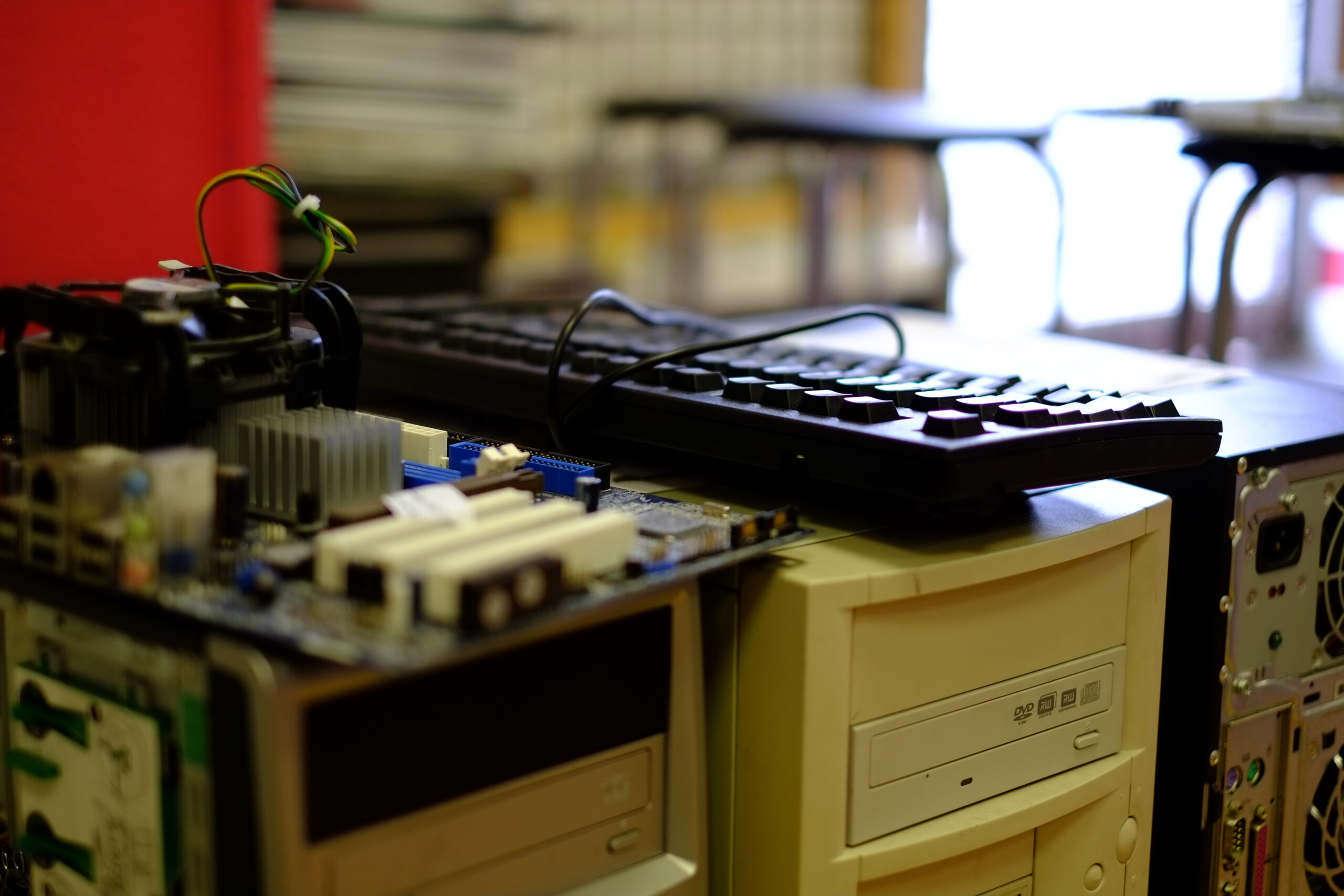 Several desktop computers in storage, with keyboards, motherboards, computer fans and other parts resting on top of them.